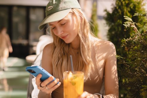 Frau schaut auf ihrem Handy nach, wie viel Geld ihr Fahrzeug beim Vermieten einbringt